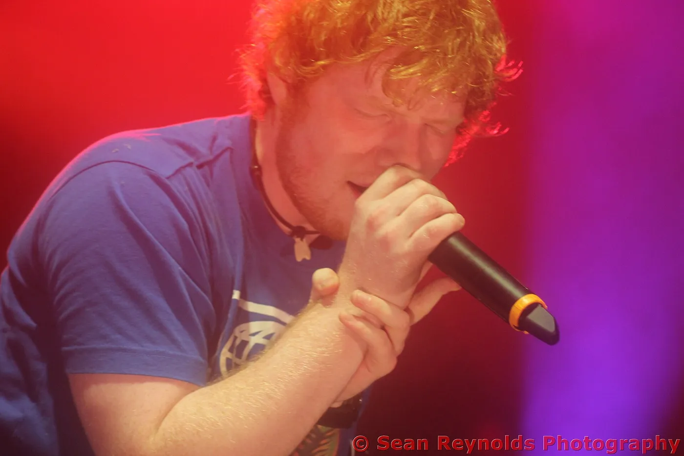 Ed Sheeran singing into a microphone